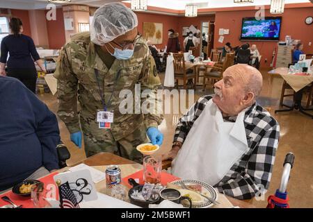 ÉTATS-UNIS Rayas Ali, Charlie Company, 104th Brigade Engineer Battalion, 44th Infantry Brigade combat Team, New Jersey Army National Guard, tient Larry Dorsett, résident du New Jersey Veterans Memorial Home à Vineland, son désert dans la salle à manger du Home à Vineland, New Jersey, le 24 février 2022. Ali sert les résidents du foyer au sein du Service des services alimentaires. Plus de 70 soldats et aviateurs de la Garde nationale du New Jersey sont des assistants infirmiers certifiés et travaillent dans les services alimentaires, le contrôle des infections, la technologie de l'information, l'enrichissement de la vie, la logistique, Et test COVID-19. (Nouveau J Banque D'Images