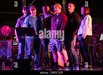 Les membres du service de la 378th Air Expeditionary Wing exécutent un karaoké de groupe en direct pendant un concert américain Concert de la bande centrale des Forces aériennes à la base aérienne de Prince Sultan, Royaume d'Arabie saoudite, 27 février 2022. La bande AFCENT soutient le moral des troupes déployées en jouant divers concerts dans la région. Banque D'Images