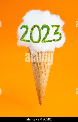 Cône de crème glacée avec remplissage de polyester flottant , lévitant sur un fond orange, avec 2023 écrit avec police lichen, flou de gros plan Banque D'Images