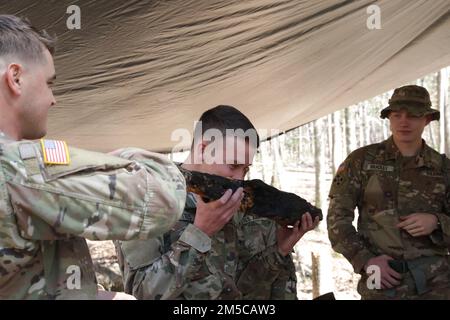 2nd le lieutenant Daniel Teed, futur étudiant en vol inscrit au cours de survie, évasion, résistance et évasion, sent un morceau de bois afin de déterminer s'il est viable pour faire du bricoler pendant l'entraînement de survie sur le terrain à fort Rucker, Alabama, 1 mars 2022. Lorsqu'on lui a demandé comment il appréciait le cours, Teed a déclaré : « c'est amusant, à la recherche de nourriture et à l'apprentissage de la manière de faire du feu de différentes façons. Être capable d'identifier différentes plantes. C'est très éducatif, et j'ai déjà apprécié cette substance, donc c'est assez cool. » Banque D'Images