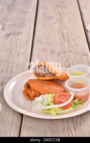 Un cliché vertical d'une Torta ahogada avec de la viande sur une assiette servie avec des sauces sur une table en bois Banque D'Images