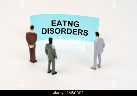 Concept médical. Des figurines miniatures de personnes se trouvent devant un signe bleu avec l'inscription - EATNG DISORDERS Banque D'Images