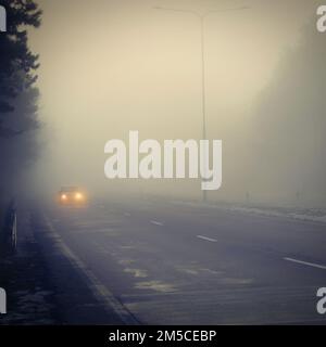 Mauvais temps conduire - foggy brumeux country road. L'autoroute - la circulation routière. L'heure d'hiver. Banque D'Images