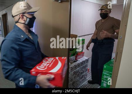220301-N-TI693-1055 STATION NAVALE ROTA, Espagne (1 mars 2022) Spécialiste culinaire 1st classe Peter Torres, à gauche, de Queens, New York, remet les magasins de navires au spécialiste des services de vente au détail Seaman Jayson Doby, de Damville, Virginie, lors d'un approvisionnement en charge à bord de la base maritime expéditionnaire USS Hershel 'Woody' Williams (ESB 4), 1 mars 2022. Hershel 'Woody' Williams est en cours de déploiement aux États-Unis Sixième zone d'exploitation de la flotte à l'appui des intérêts nationaux et de la sécurité des États-Unis en Europe et en Afrique. Banque D'Images