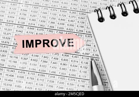 Concept d'entreprise. Sur la table parmi les rapports est un bloc-notes, un stylo avec une flèche avec l'inscription - AMÉLIORER Banque D'Images
