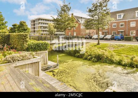 une rivière au milieu d'un quartier résidentiel avec des arbres et des fleurs de chaque côté de l'eau, il y a un petit pont Banque D'Images