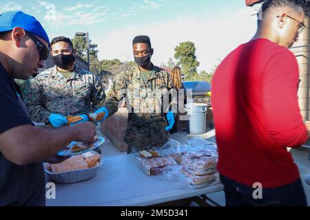 Les bénévoles servent de la nourriture aux membres du Régiment des guerriers blessés et à leurs familles lors d'une prise de vue lors du lancement des épreuves du corps marin de la côte ouest (MCT) à bord du camp de base du corps marin Pendleton, Californie, 3 mars 2022. Les MCT ont lieu dans le but de maintenir l'esprit de guerrier compétitif, de construire la camaraderie et de fournir un lieu de sélection des participants pour les Jeux de guerrier du DoD 2022. Banque D'Images