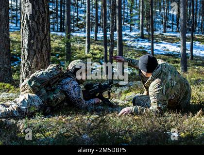 20220303-A-VU095-1084 – A ÉTATS-UNIS Le Béret vert de l'armée affecté au Groupe des 10th forces spéciales instruit un soldat de la Garde nationale lettone sur des positions d'analyse de terrain et de surveillance lors d'un exercice d'entraînement sur le terrain dans les forêts de Lettonie, 2 mars 2022. La formation bilatérale crée une interopérabilité avec les alliés de l'OTAN, améliore la préparation militaire et renforce la confiance commune tout en favorisant la paix et la stabilité dans la région. Banque D'Images