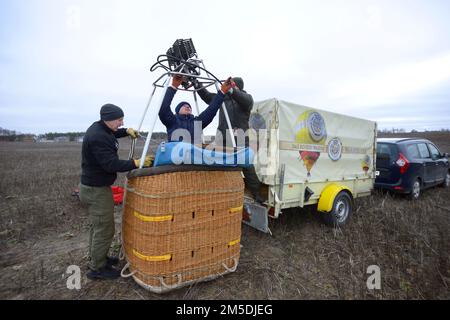 Préparatifs pour le vol en montgolfière: Les travailleurs hommes ont installé le brûleur à gaz sur le dessus du panier, de la voiture et de la remorque avec l'équipement sur un fond. Kiev, Ukraine Banque D'Images