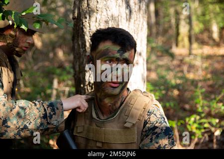 ÉTATS-UNIS Le groupe des Marine corps PFC. Noah Reynard reçoit de la peinture de camouflage des États-Unis Kylie Webb, ingénieur de combat à l'école Marine corps Engineer, au cours de la troisième phase d'évaluation du camp de corps de Marine Lejeune, en Caroline du Nord, en 4 mars 2022. Les ingénieurs de combat effectuent diverses tâches, notamment la construction de structures, la reconnaissance d'ingénieurs, l'installation de systèmes d'obstacles et la conduite d'opérations de braconnage dans le cadre du cours de base de 21st siècles d'ingénieurs de combat. Banque D'Images