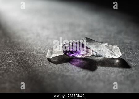 Petits cristaux de pierres minérales Purple Amethyst et Pure Quartz rétro-éclairé sur fond sombre Banque D'Images