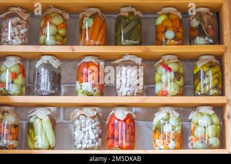 Légumes marinés, café sec, bouchons de bouteille dans des pots en verre sur les étagères de stockage Banque D'Images