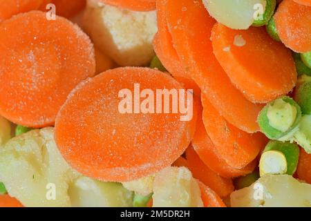 Légumes frais surgelés, gros plan. Vue rapprochée de la soupe de légumes avec carottes, petits pois, chou-fleur et maïs en fond d'eau. Texture de Banque D'Images