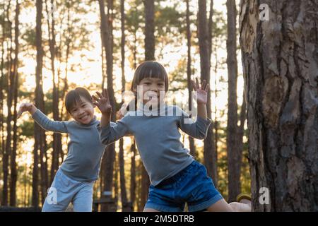 Petites sœurs amusantes qui se cachent derrière l'arbre dans le parc d'hiver. Mignon sourire enfant jouant cacher et chercher dans la forêt. Les enfants regardent dans le chamer Banque D'Images