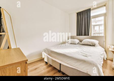 une chambre avec un lit, une commode et un miroir sur le mur en face de la chambre est très clair parquet Banque D'Images