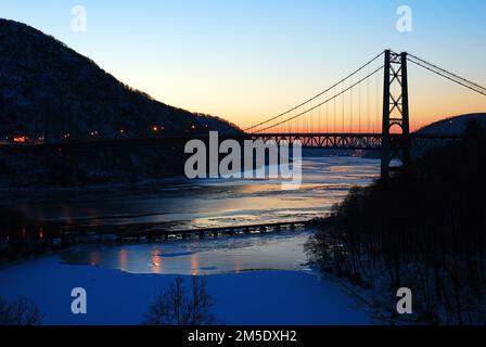 Le soleil se lève sur la glace de l'Hudson River et du pont de Bear Mountain lors d'une journée d'hiver froide dans la vallée de l'Hudson, dans l'État de New York Banque D'Images