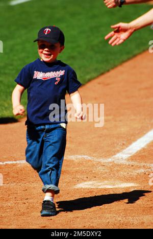 Un jeune garçon souriant court sur la plaque d'accueil lors d'une course post-match autour des bases de Target Field, stade des Minnesota Twins Banque D'Images