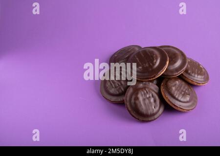 photo de nombreux biscuits ronds enrobés de chocolat sur fond violet Banque D'Images