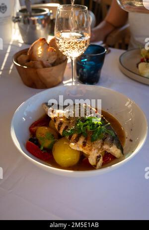 Cuisine provençale, filet grillé de poisson blanc au seabass servi avec des pommes de terre, des tomates et du jus de poisson Bouillabaisse dans le restaurant français Banque D'Images