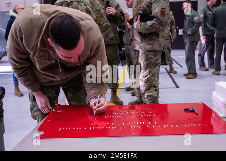 ÉTATS-UNIS Le Sgt Duane Jongeling, membre de la Garde nationale aérienne, spécialiste de la contre-mesure électronique de l'escadre de chasse 114th, signe son nom à la plaque rouge que son équipe a reçu lors de la première fusillade en Turquie sur Joe Foss Field, S.D., 6 mars 2022. Le but de la fusillade en Turquie était de renforcer le moral et de créer un esprit de compétition au sein des groupes entretien et opérations. Banque D'Images