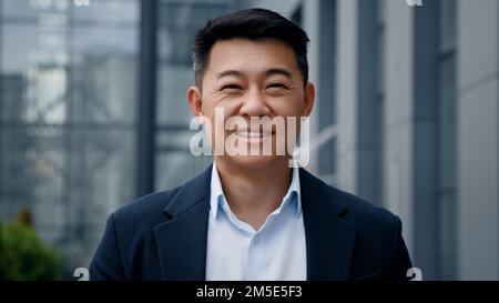 Portrait pensive rêve pensant réalisateur architecte homme dans la ville à l'extérieur en regardant loin sur le bâtiment de bureau tourner la tête en regardant l'appareil photo asiatique 40s Banque D'Images