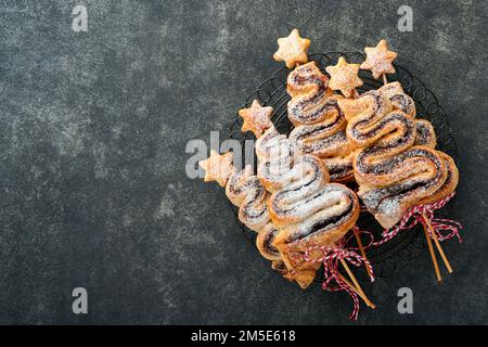 Gâteau feuilleté en forme d'arbre de Noël avec garniture au chocolat, poudre de sucre et sucettes sur fond sombre. Noël, hors-d'œuvre du nouvel an. Festi Banque D'Images