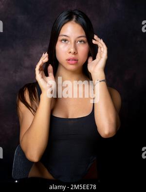 Demi-corps Portrait de femelle de Teen multiracial assis avec les mains frayant le visage Banque D'Images