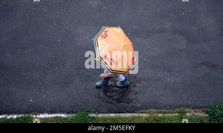 Kiev, Ukraine 25 août 2020: Un garçon avec un parapluie marche dans une flaque Banque D'Images