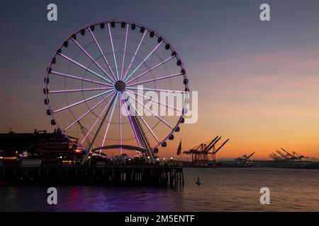 WA22872-00...WASHINGTON - la Grande roue de Seattle au coucher du soleil, située sur Elliott Bay avec le port de Seattle au loin. Banque D'Images