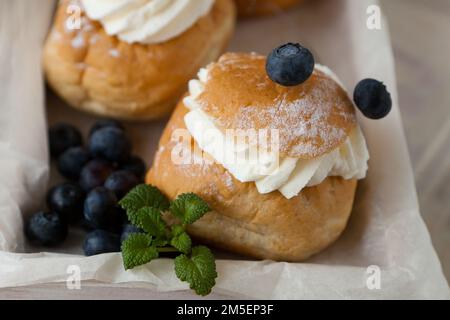 Pain suédois Semla ou Shrove avec pain de blé léger et pâte d'amande et garniture à la crème fouettée, menthe Banque D'Images