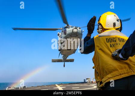 220309-N-EM691-1004 OCÉAN ATLANTIQUE (9 mars 2022) €– des marins affectés au destroyer de missile guidé de la classe Arleigh Burke USS les Sullivans (DDG 68) guident un faucon MH-60s affecté aux 'Ghost Riders' de l'Escadron de combat de la mer (HSC) 28 sur le pont de vol, 9 mars. Les Sullivans sont déployés sur le théâtre d'opérations européen et participent à une série d'activités maritimes à l'appui des États-Unis Sixième flotte et alliés de l'OTAN. Banque D'Images