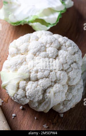 Chou-fleur entier frais sur la planche à découper. Chou-fleur blanc sur la planche de bois avec couteau. Banque D'Images