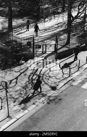 Une échelle verticale de gris de personnes marchant sur le trottoir dans les rues de Paris par une journée ensoleillée Banque D'Images