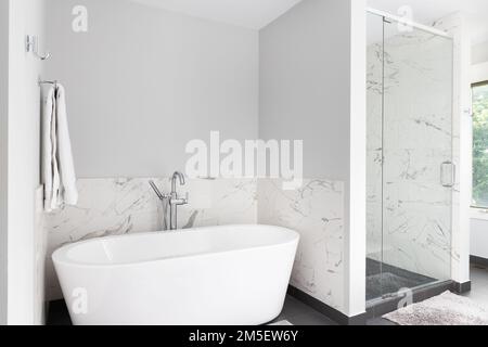 Une baignoire et une douche indépendantes avec des murs en marbre et un sol carrelé sombre. Banque D'Images