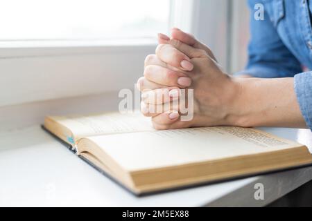 Mains d'une femme méconnaissable avec Bible priant Banque D'Images