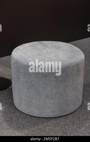Tabouret de pied rond en tissu gris au plancher de la moquette dans la salle de séjour Banque D'Images