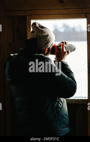 Un photographe masculin photographie des photographies d'oiseaux depuis la couverture de Birding Box Banque D'Images
