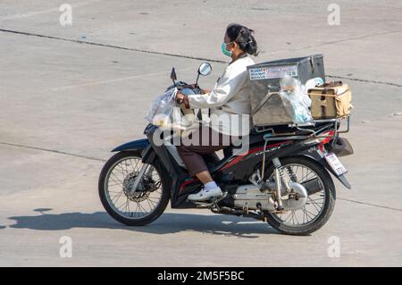 SAMUT PRAKAN, THAÏLANDE, FÉVRIER 23 2022, Une femme avec une charge conduit une moto Banque D'Images