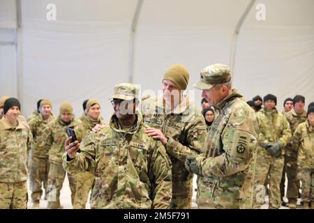 Le général de division Jeffery Broadwater, commandant adjoint du V corps, a parlé avec le 2nd Lt. Akil Errapotu, officier d'artillerie, quartier général et compagnie de quartier général, 1-3rd Bataillon d'attaque avant de présenter une pièce à Errapotu lors d'une visite à la base aérienne de Lielvārde, 10 mars 2022. Le capitaine Dylan Benit (au centre), commandant de la Compagnie du siège et du quartier général, 1-3rd Attack Battalion, a parlé au téléphone à la femme d’Errapotu de son exécution au cours de l’exercice Sabre Strike 22. Broadwater a rencontré les soldats du bataillon d'attaque 1-3rd et a reconnu quatre membres de l'unité pour leur performance. Banque D'Images