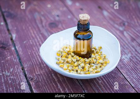 Thé sec à base de fines herbes de grandes fleurs de mullein ou de thapsus de Verbascum dans un petit bol en argile avec une bouteille de médecine brune sur fond de bois. Banque D'Images