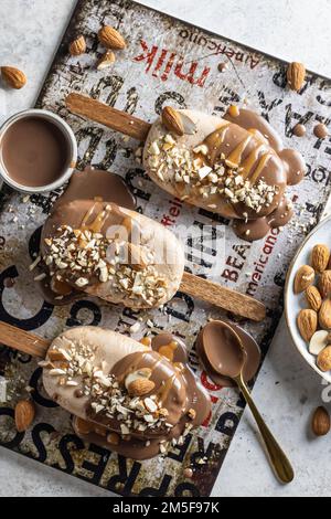 Quelques délicieuses glaces végétaliennes maison ou des popsicles couverts de chocolat et de noix, vue sur le dessus, plat. Verticale Banque D'Images