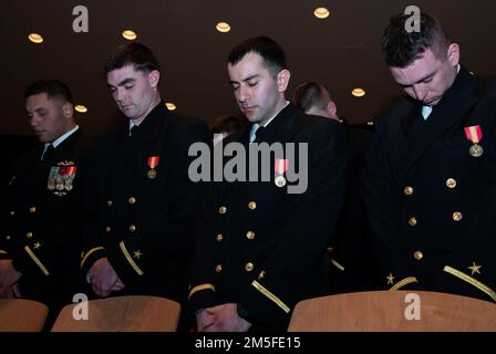 NEWPORT, RI (11 mars 2022) élèves de la classe 07-22 de l'école candidate d'officier (OCS) au Commandement de la formation d'officier Newport (OTCN), Rhode Island, abaissent la tête pour l'invocation lors de leur cérémonie de remise des diplômes, 11 mars. OCS développe des civils et des marins de la flotte en officiers nouvellement commissionnés moralement, mentalement et physiquement tout en les inculquant avec les idéaux les plus élevés d'honneur, de courage et d'engagement pour le service dans la flotte en tant qu'officiers de la marine. Banque D'Images