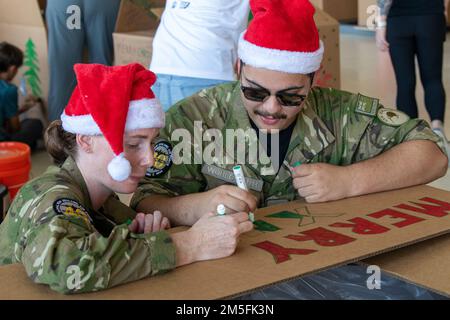 La SGT de la Royal New Zealand Air Force, Julia McLaughlin, et le principal artisan aéroporté Matthew Wohlgemuth décorent une boîte à colis lors de l'opération Christmas Drop 2022 à la base aérienne d'Andersen, Guam, le 3 décembre 2022. OCD est la plus longue mission d’aide humanitaire et de secours en cas de catastrophe du ministère de la Défense et fournit des secours à plus de 50 îles dans tout le Pacifique. Des opérations comme OCD offrent aux États-Unis et à leurs partenaires l'occasion d'améliorer leurs capacités opérationnelles conjointes et de maintenir leur état de préparation aux situations d'urgence réelles. Banque D'Images