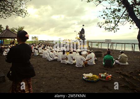 Un clan balinais est assis ensemble alors qu'ils se préparent à un rituel pour honorer et purifier les esprits de leurs derniers membres de la famille, sur une plage près du temple Goa Lawah à Dawan, Klungkung, Bali, Indonésie. Banque D'Images