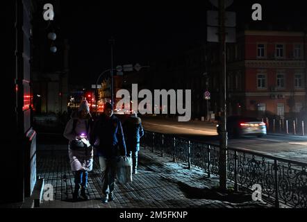 Kiev, Ukraine. 26th décembre 2022. Les gens descendent une rue sombre pendant une panne de courant à Kiev. L'armée russe a mené des attaques massives de roquettes et de drones kamikaze sur les infrastructures énergétiques ukrainiennes. Après de graves dommages au réseau électrique dans de nombreuses villes d'Ukraine, la compagnie nationale d'électricité Ukrenergo a introduit des coupures d'électricité d'urgence et toutes les heures. Crédit : SOPA Images Limited/Alamy Live News Banque D'Images