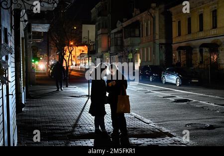 Kiev, Ukraine. 26th décembre 2022. Les femmes utilisant un smartphone à l'arrêt de bus pendant une panne de courant à Kiev. L'armée russe a mené des attaques massives de roquettes et de drones kamikaze sur les infrastructures énergétiques ukrainiennes. Après de graves dommages au réseau électrique dans de nombreuses villes d'Ukraine, la compagnie nationale d'électricité Ukrenergo a introduit des coupures d'électricité d'urgence et toutes les heures. Crédit : SOPA Images Limited/Alamy Live News Banque D'Images