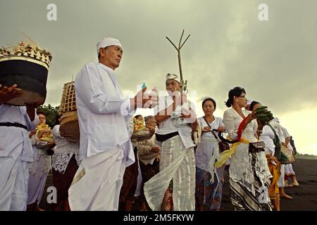 Un clan balinais se prépare à mener un rituel pour honorer et purifier les esprits de leurs membres de famille tardifs, sur une plage près du temple Goa Lawah à Dawan, Klungkung, Bali, Indonésie. Banque D'Images