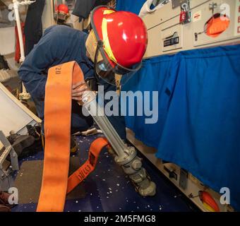 220314-N-KW492-1028 OCÉAN PACIFIQUE (14 mars 2022) le pompier Jonathan Gonzalez, d'El Paso, Texas, simule l'assèchement d'un espace à l'aide d'un derbyshire lors d'un exercice d'inondation à bord du destroyer de missiles guidés de classe Arleigh Burke USS Milius (DDG 69). Milius est affecté au Destroyer Squadron (DESRON) 15, le plus grand DESRON déployé à l’avant de la Marine et à la principale force de combat de la flotte américaine 7th, et est en cours de soutien à une Indo-Pacific libre et ouverte. Banque D'Images