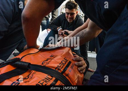 OCÉAN PACIFIQUE (14 mars 2022) le Matelot de 1re classe Josue Gonzalez-Pagan, de Tampa, Floride, aide à placer une victime simulée dans un brancard à manchon de la Reeve dans le cadre d’un exercice médical d’urgence sur l’aile de pont du navire de transport amphibie USS John P. Murtha (LPD 26), 14 mars. John P. Murtha mène actuellement des opérations de routine dans la flotte américaine 3rd. Banque D'Images