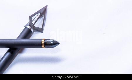 Une tête large à trois lames à l'extrémité d'une flèche en carbone et une autre avec un point de champ sur un fond blanc avec de la place pour le texte Banque D'Images